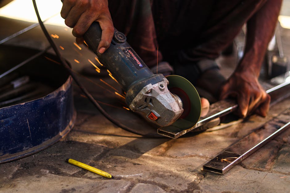 Close-up of a worker using an angle grinder to cut metal, sparks flying.