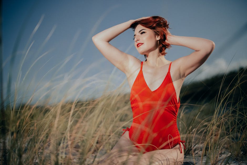 A woman in a red swimsuit poses gracefully on a beach in Melbourne.