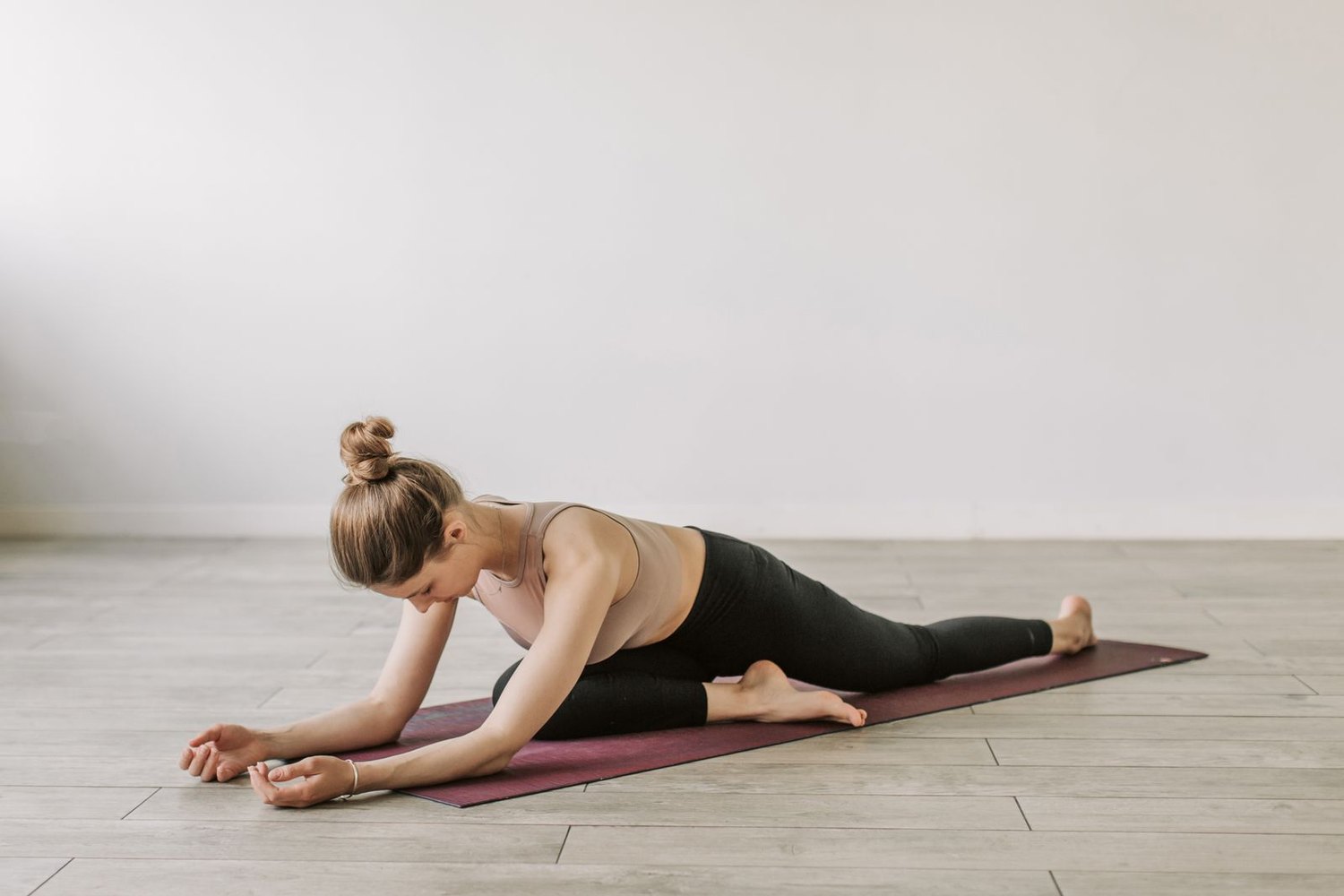 Woman in black leggings stretching on a yoga mat