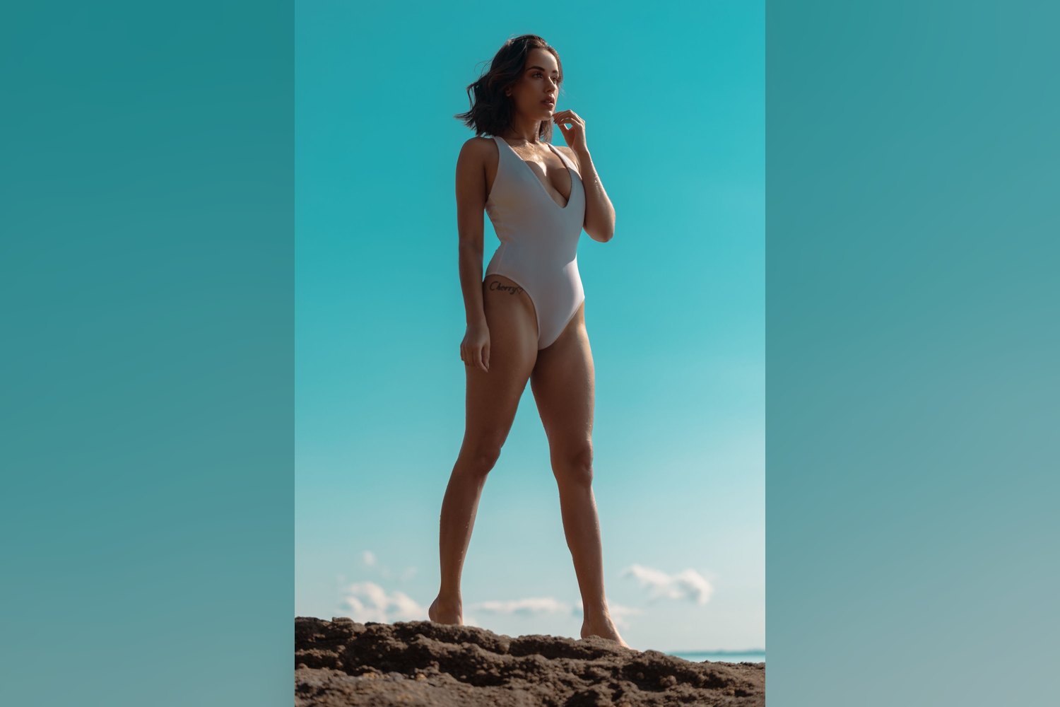 Woman in a white high-cut one-piece swimsuit standing on a beach